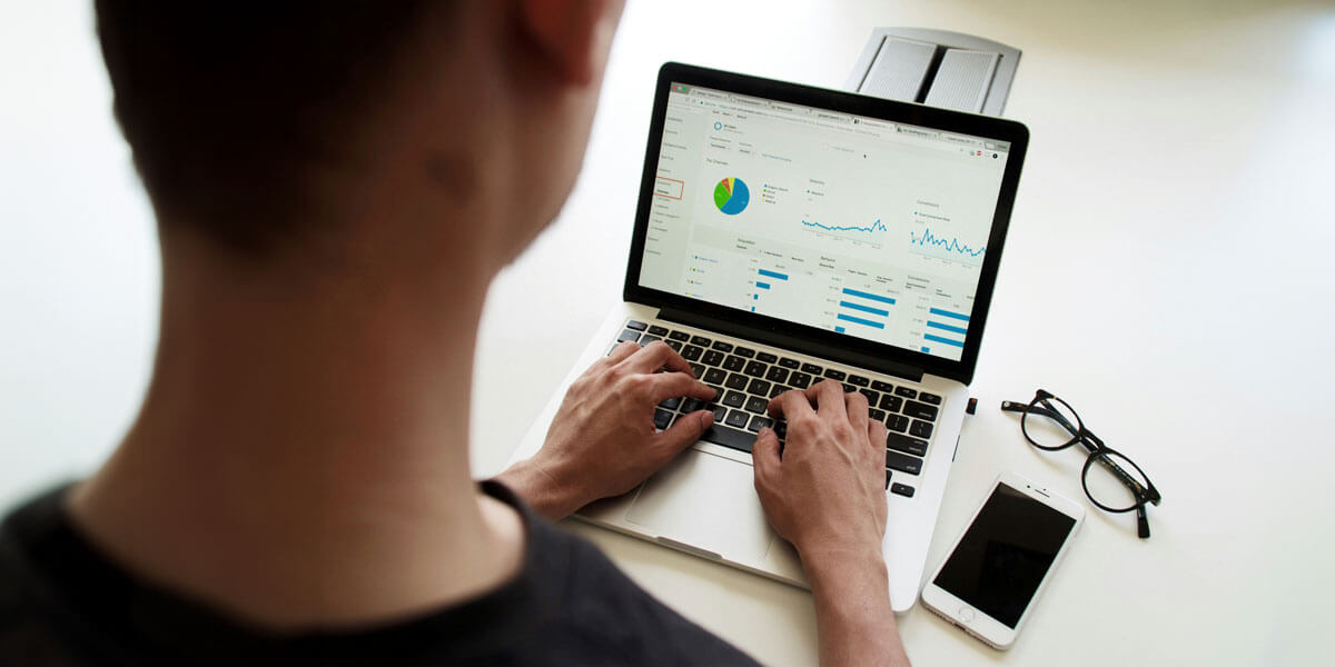 A person typing on a laptop, focused on a graph displayed on the screen, illustrating data analysis or progress.